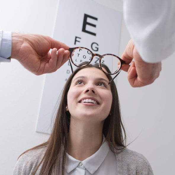 An Optometrist Holds Glasses in Front of a  Patient — Peninsula Eyecare Izzards Optometrists in Woy Woy, NSW