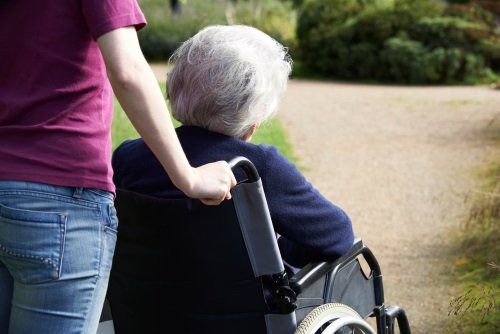 una signora anziana su una sedia rotella e una donna che accompagna
