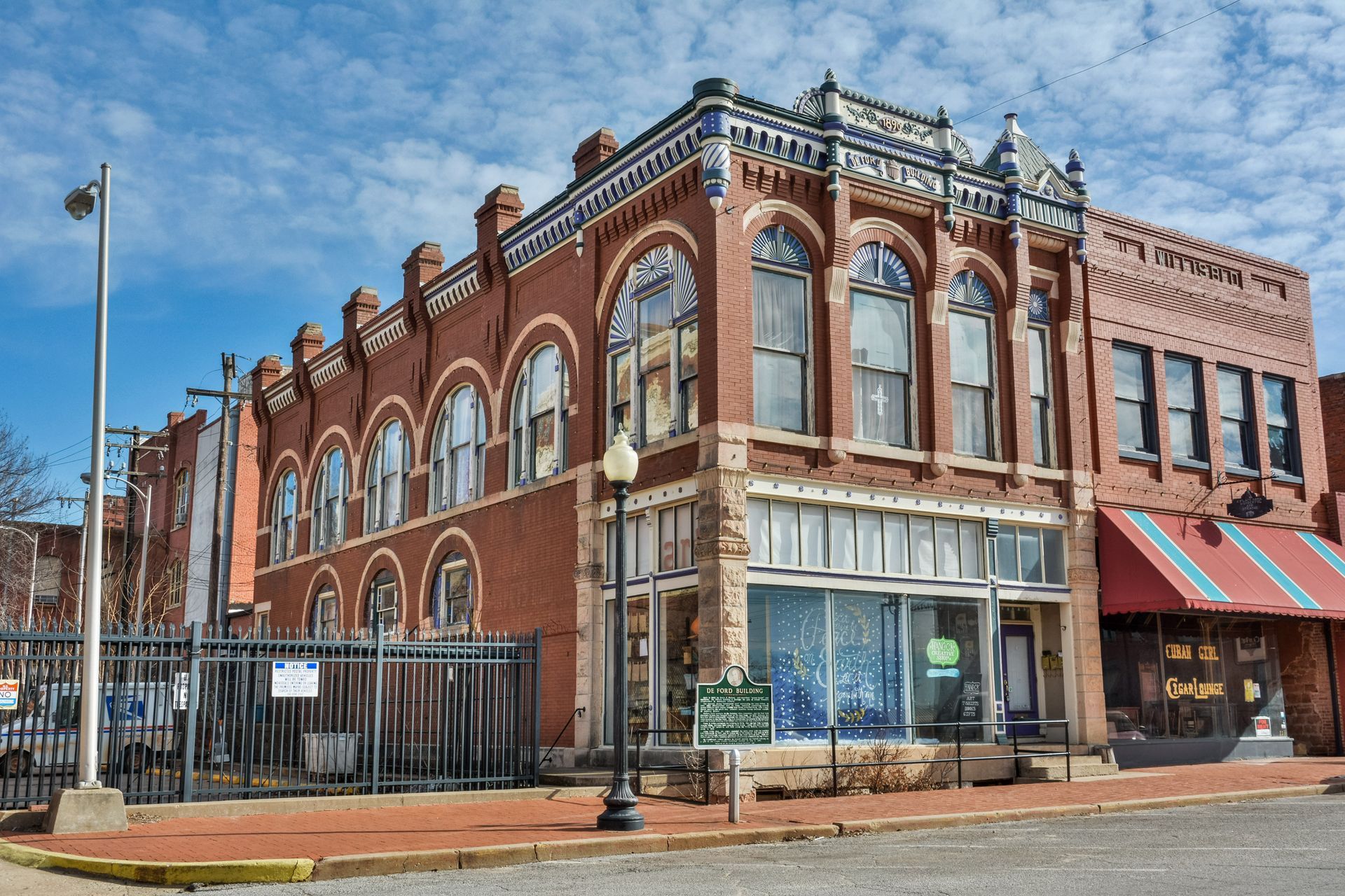 Red brick building with arched windows, shopfront, and decorative blue and white trim.
