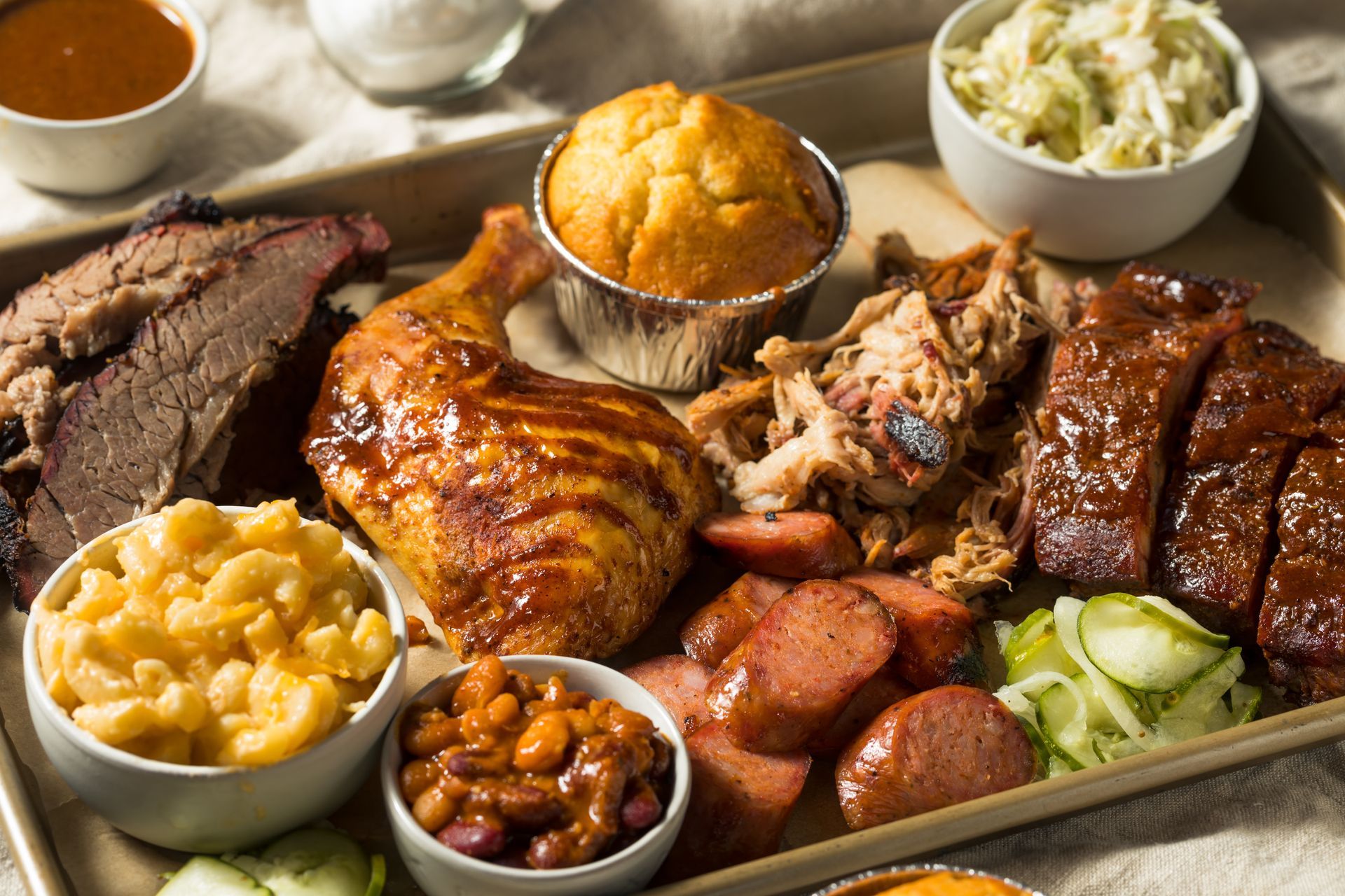 Barbecue platter with brisket, chicken, ribs, sides like mac and cheese, slaw, and beans.