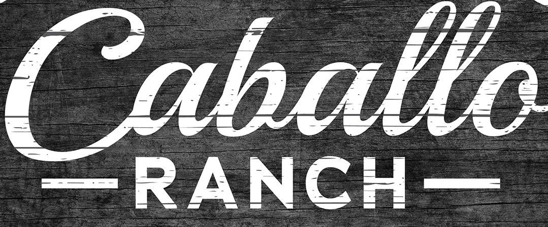 Caballo Ranch sign in white script on dark wood background.