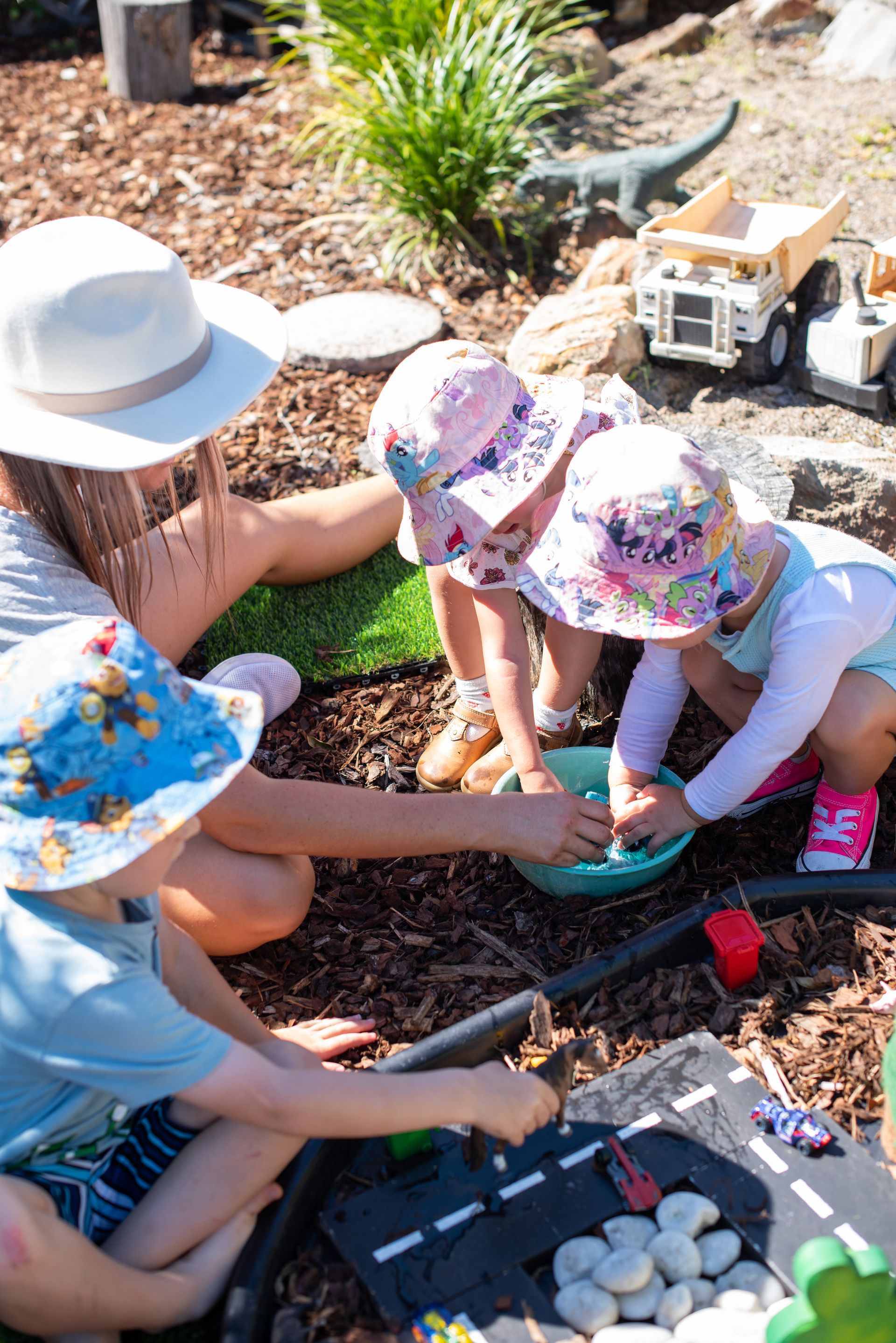 Children and adult playing with water and toys in a garden setting.