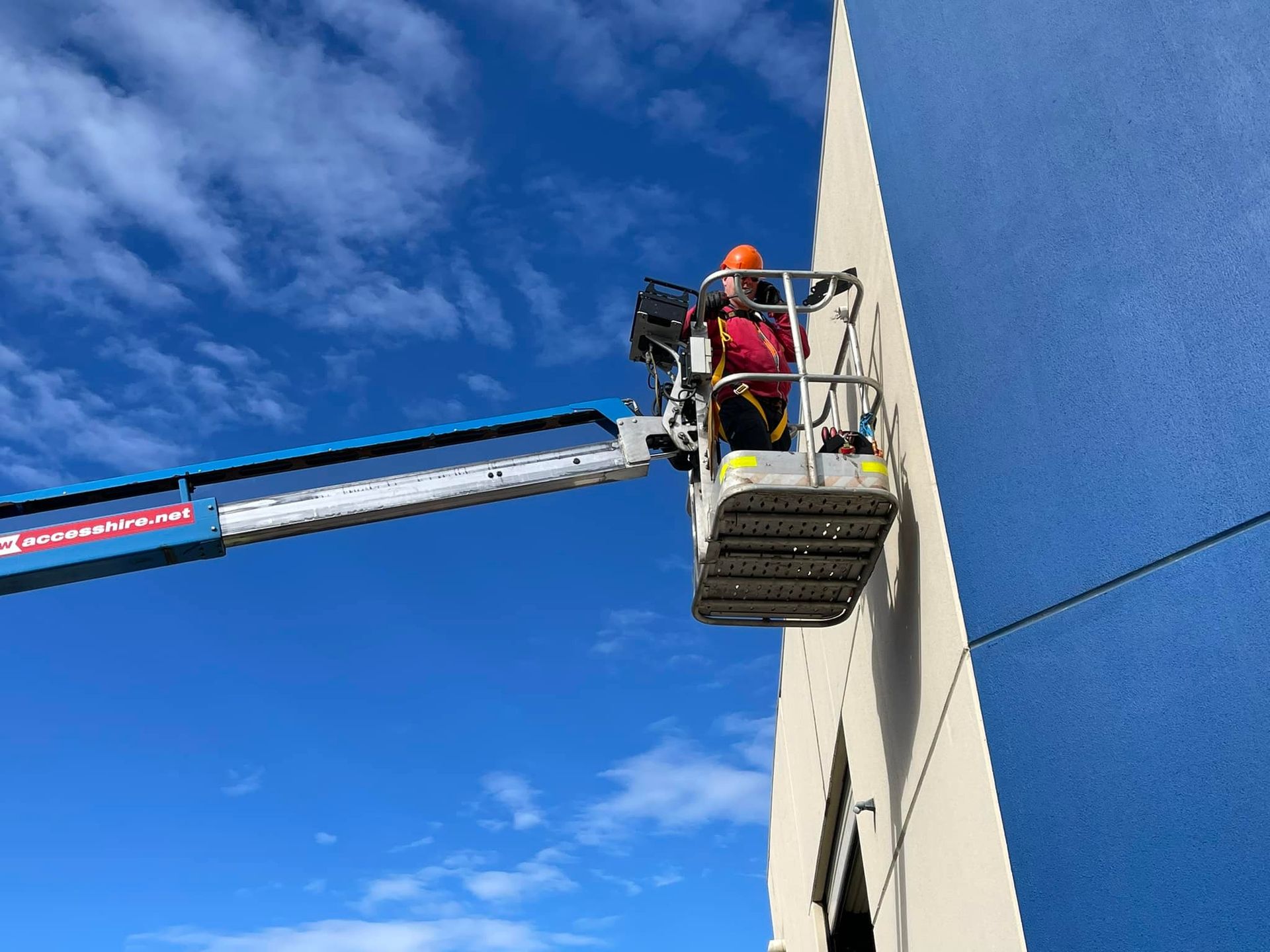 A Man is outside a commercial building installing emergency flood LED lights. — Gunter Electrical In Kariong, NSW
