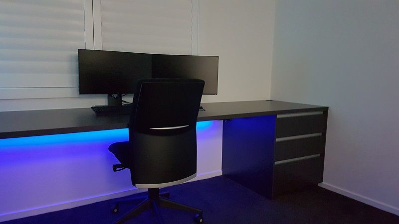 A Computer Desk With Two Monitors and a Chair in a Room — Gunter Electrical In Kariong, NSW