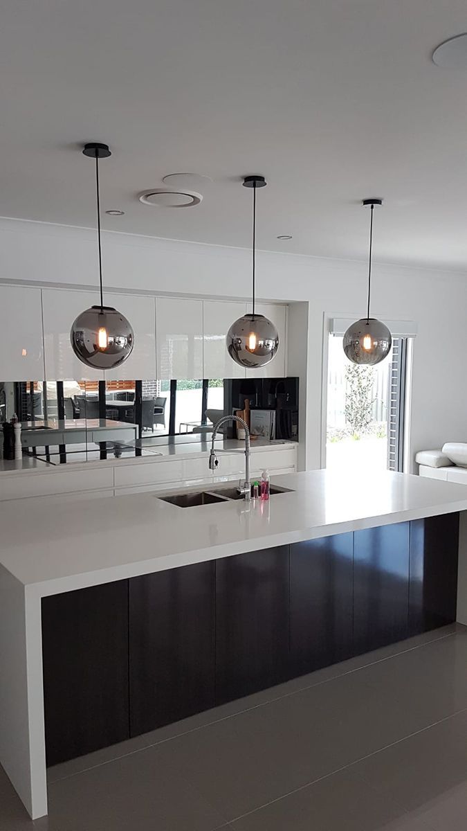 A Kitchen With a Large Island and Pendant Lights Hanging From the Ceiling — Gunter Electrical In Kariong, NSW