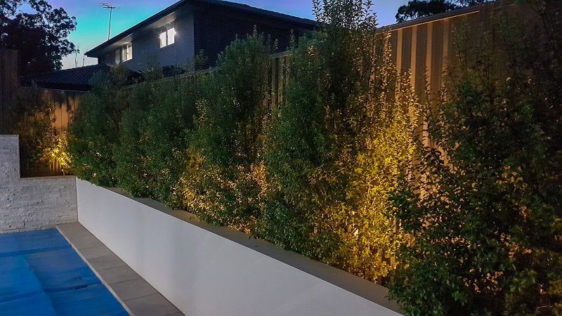 A Fence Surrounding a Swimming Pool With a House in the Background — Gunter Electrical In Kariong, NSW