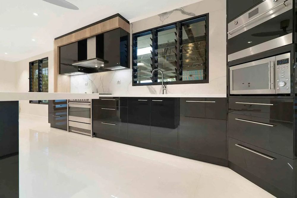 A Kitchen With Black Cabinets and Stainless Steel Appliances — Designer Kitchens in Berrimah, NT