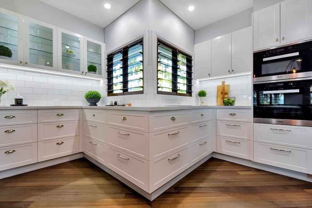 A Kitchen With White Cabinets and Black Appliances — Designer Kitchens in Berrimah, NT