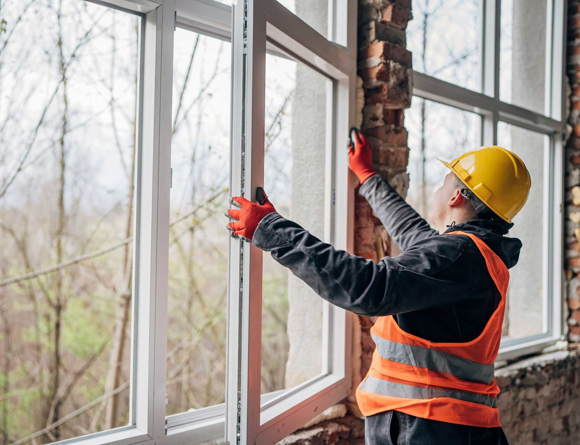 A worker installs and adjusts large window frames.