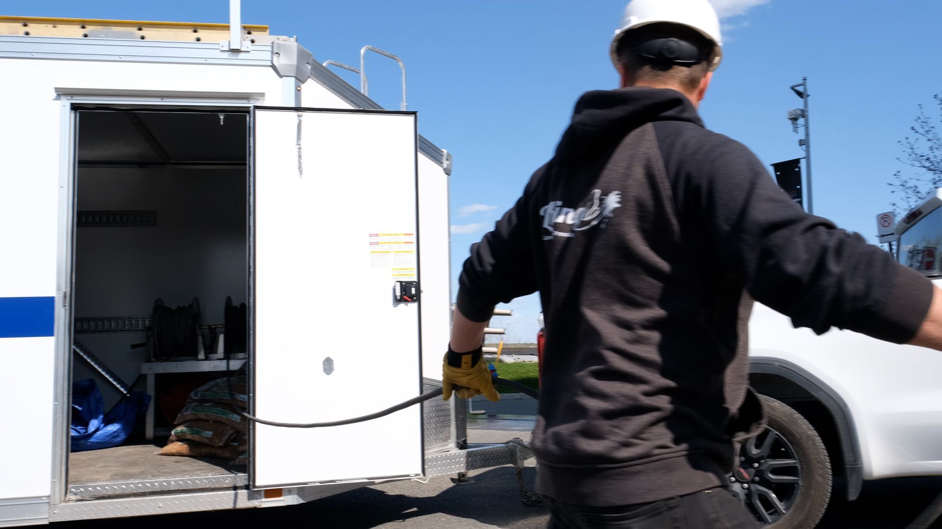 Un homme portant un casque de sécurité se tient devant un camion blanc.