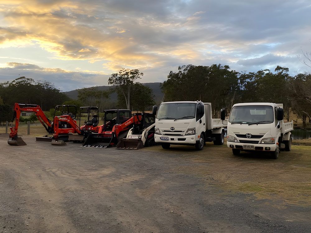 View Front Orange Excavator, White Positrack And White Tipper Trucks — Quality Excavation in Boomerang Beach, NSW