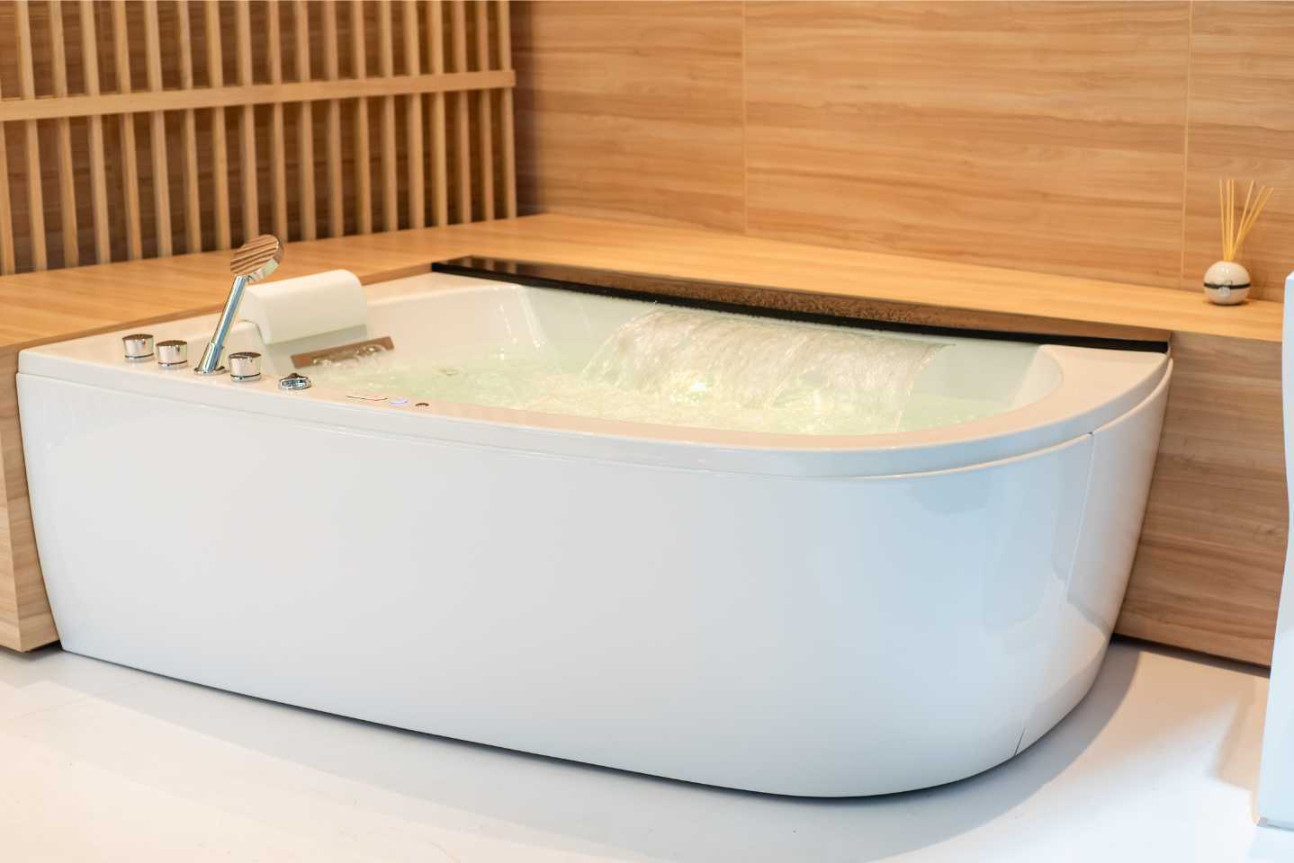 A white bathtub is sitting in a bathroom next to a wooden wall.