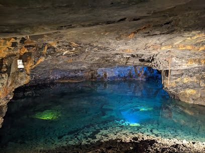 Underground cave with clear turquoise water reflecting the dark, textured ceiling.