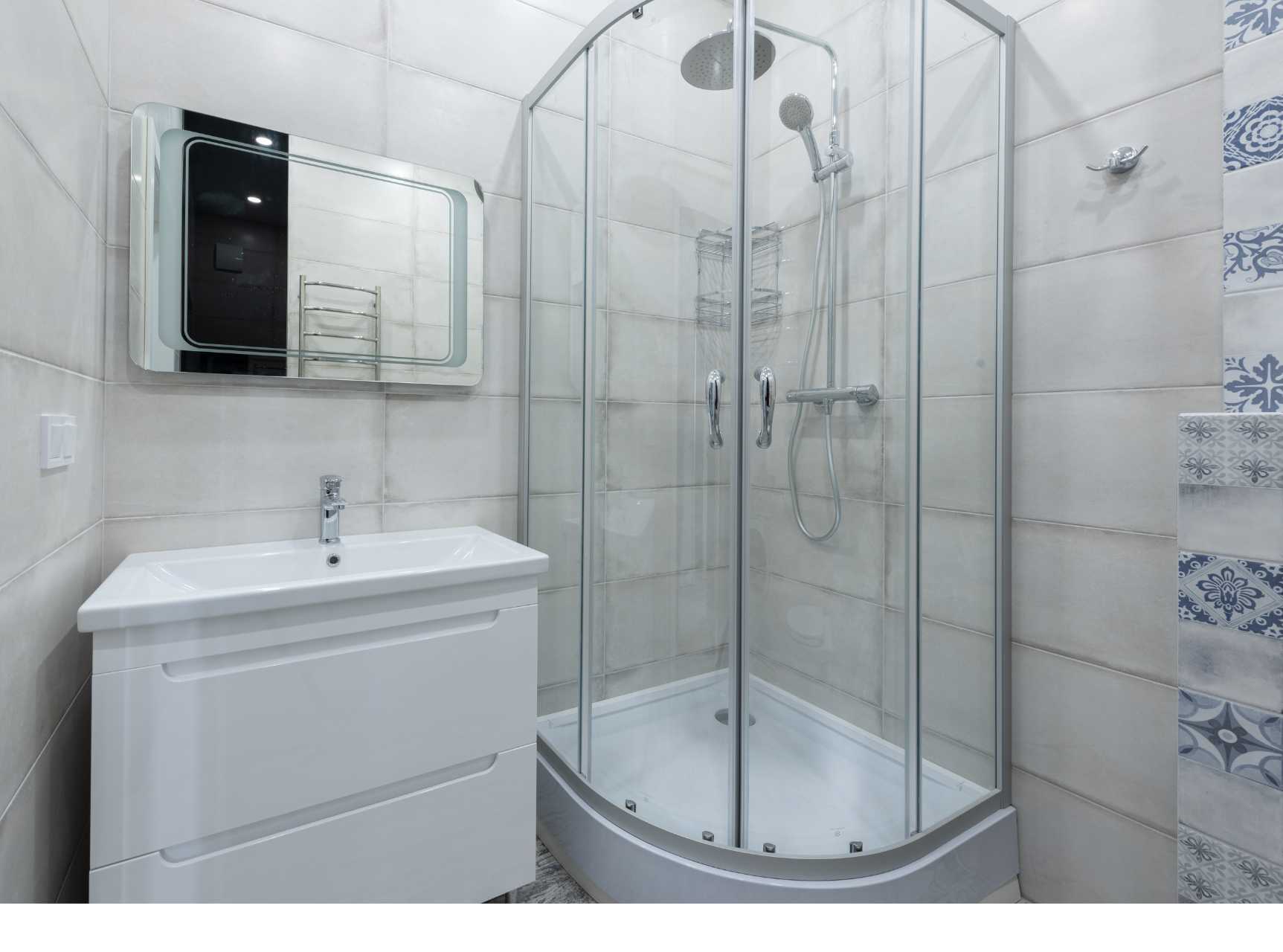 A bathroom with a shower stall , sink and mirror.