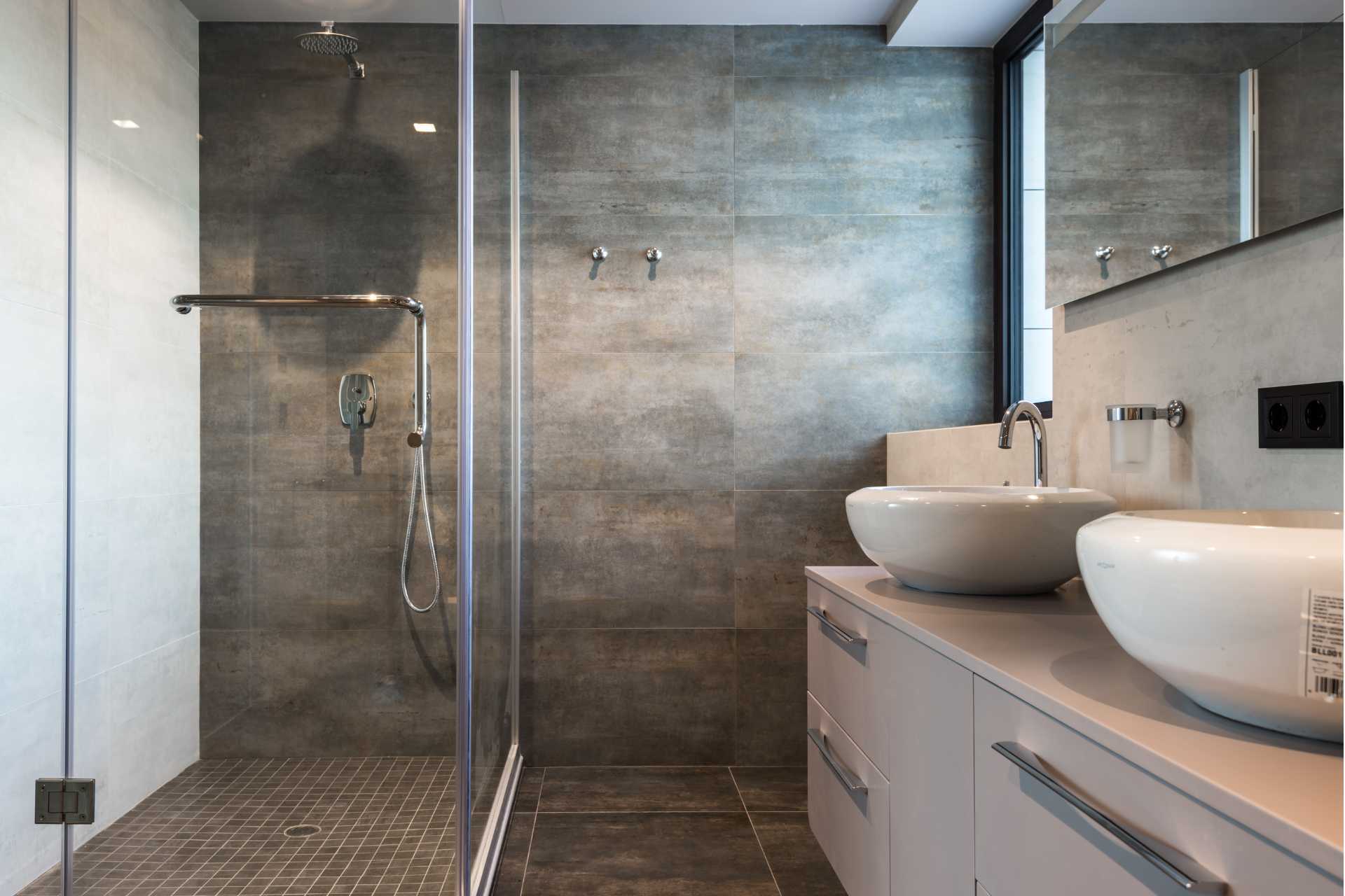 A bathroom with two sinks and a walk in shower.