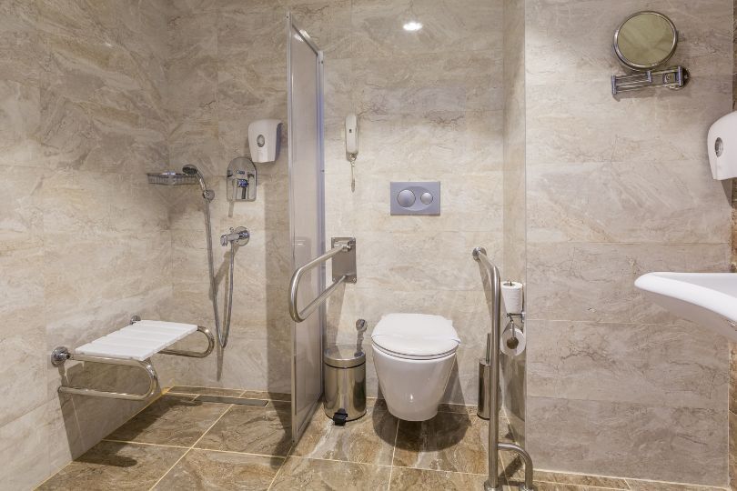 A handicapped bathroom with a toilet , sink and shower.