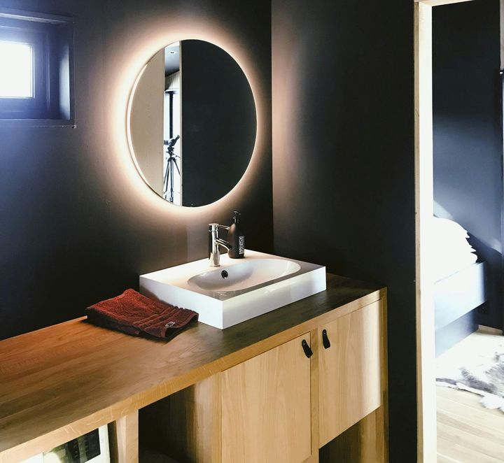 A bathroom with a sink and a round mirror