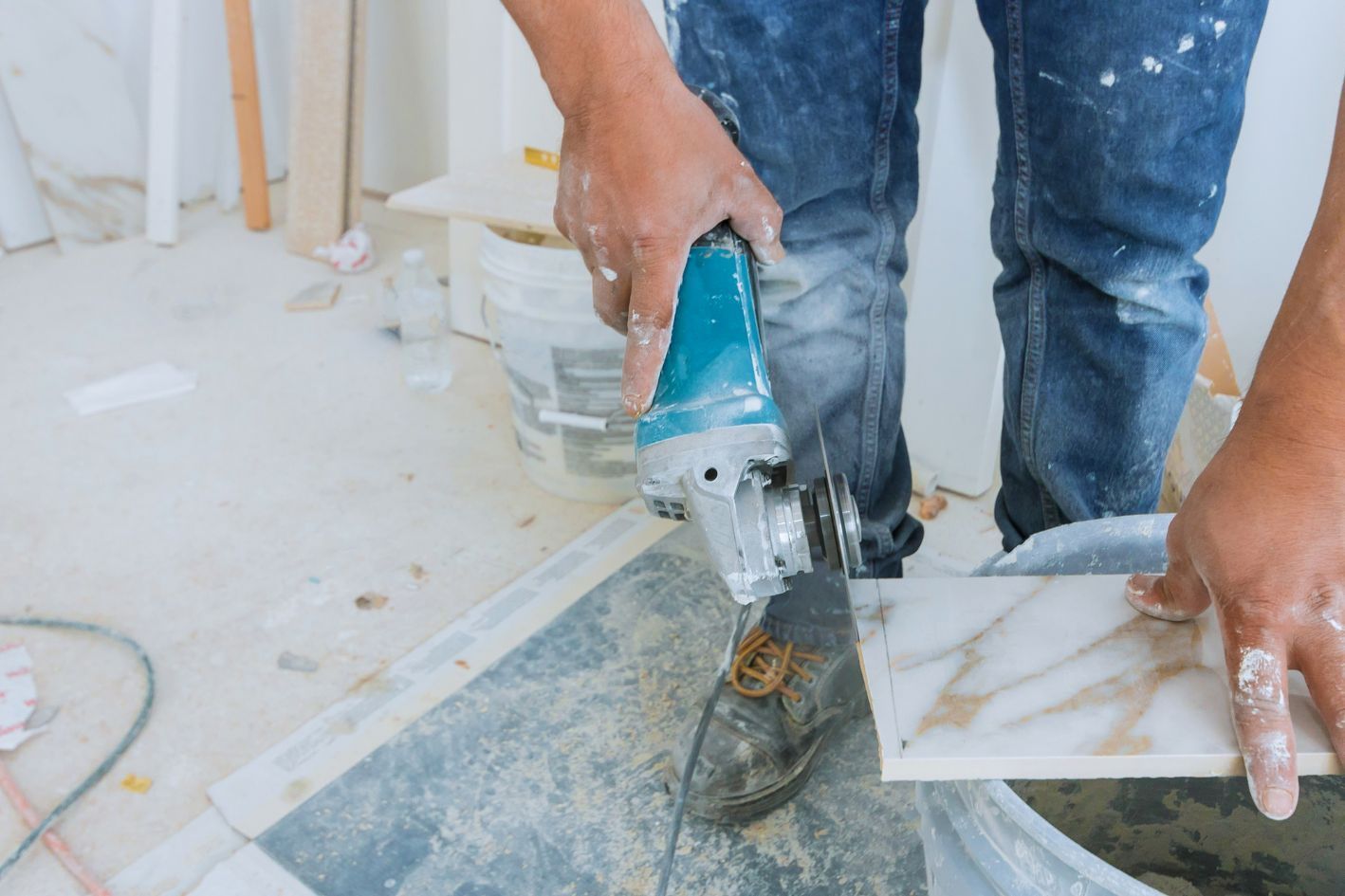 Person cutting tile with a power saw, inside a room under renovation.