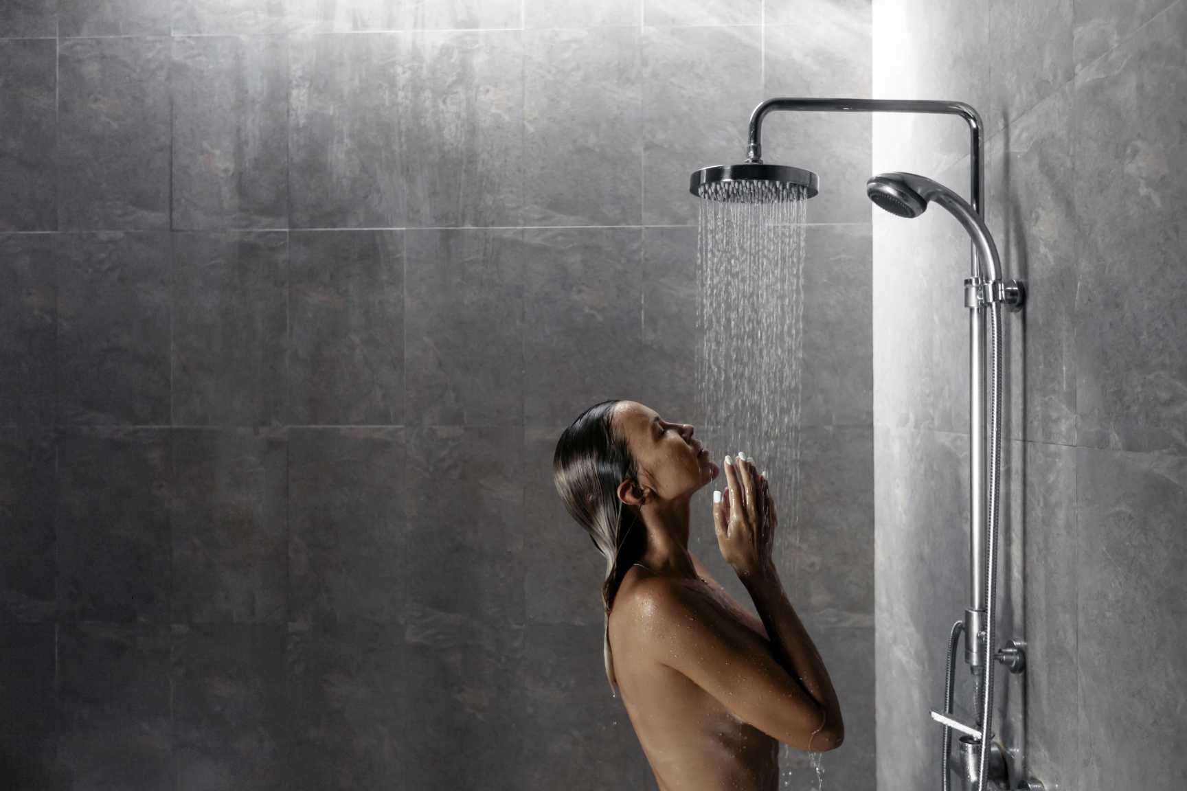 A woman is taking a shower in a bathroom with a shower head.