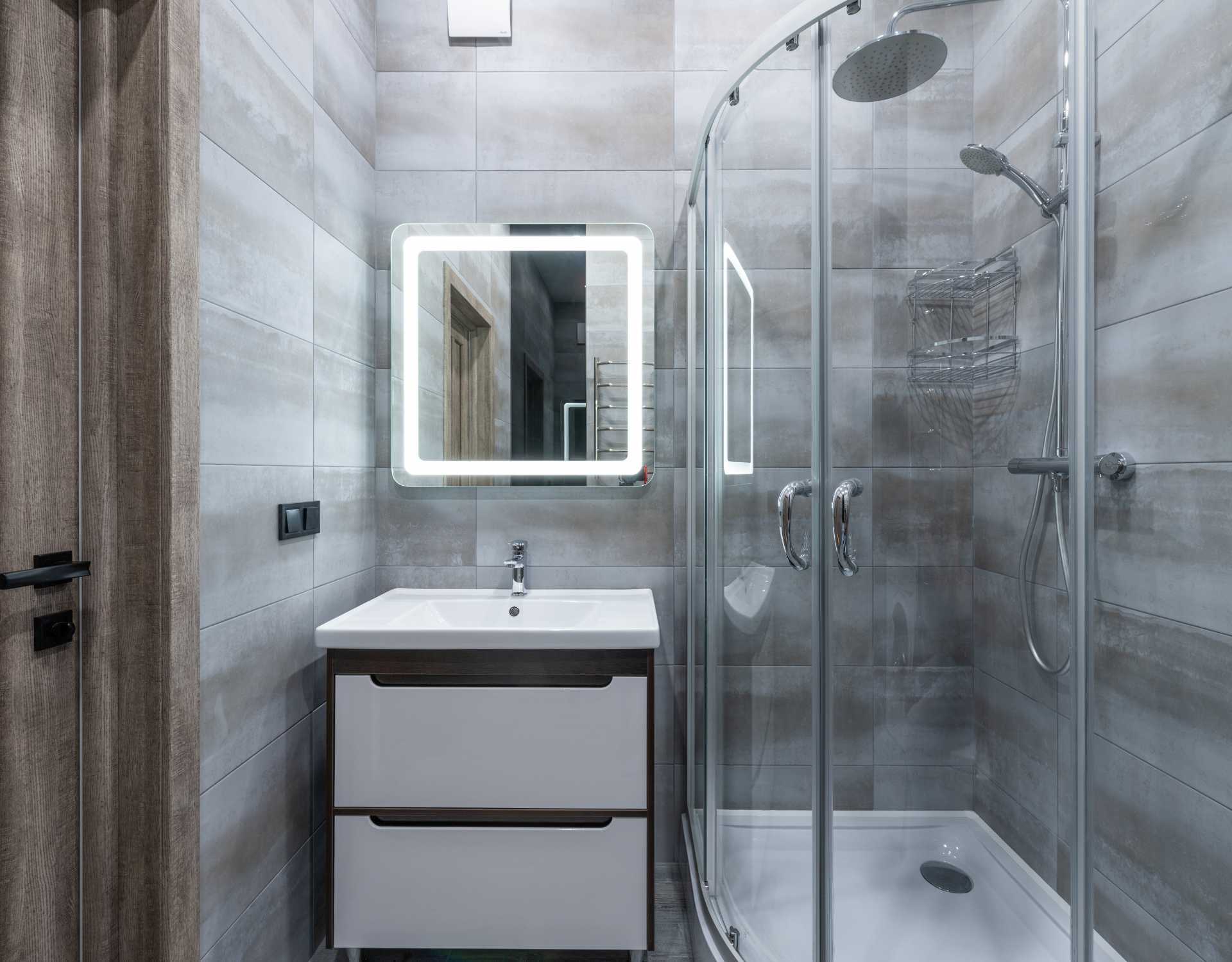A bathroom with a sink , mirror and shower stall.