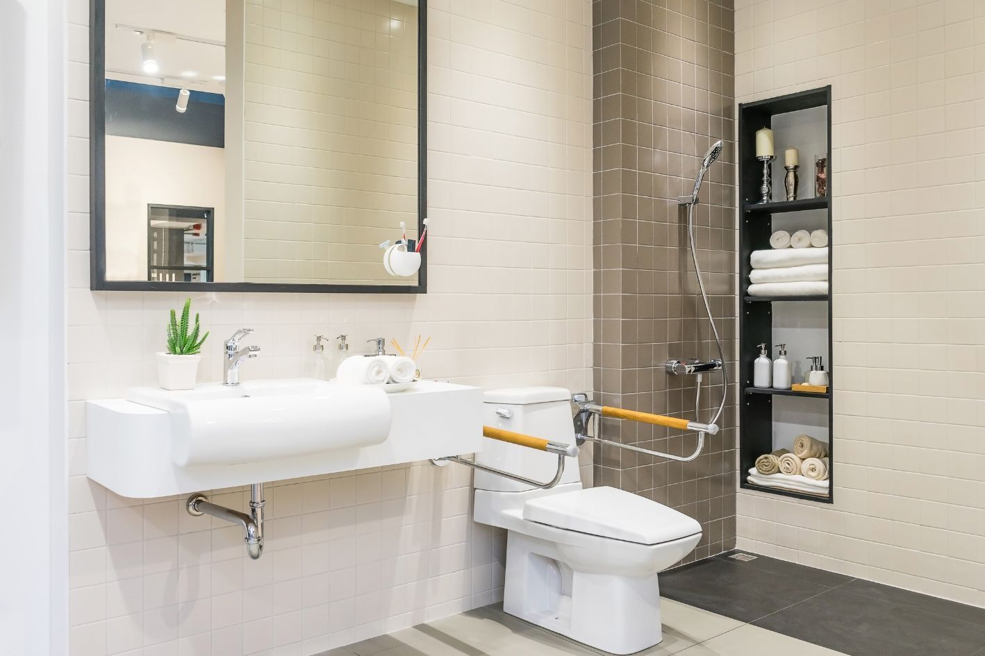 Accessible bathroom with a wall-mounted sink, toilet with grab bar, and a shower with built-in shelving.
