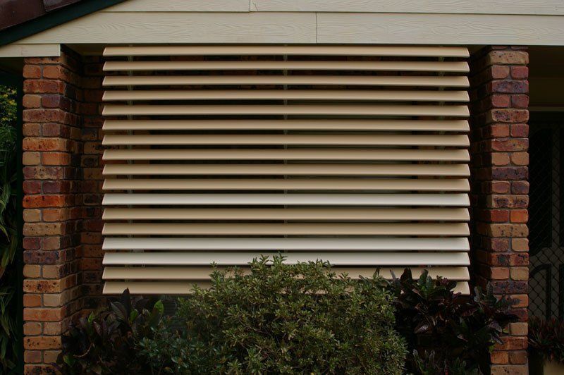 House With a Brick Wall and a Window With Blinds on It — Blind Outfitters in Millaa Millaa, QLD
