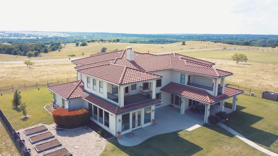 An aerial view of a large house in the middle of a field.