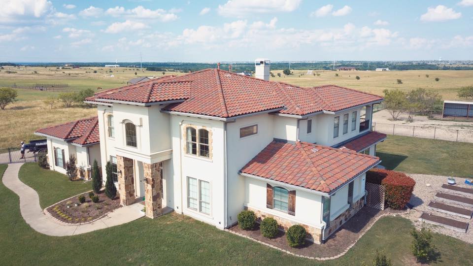 An aerial view of a large white house with a red tile roof.