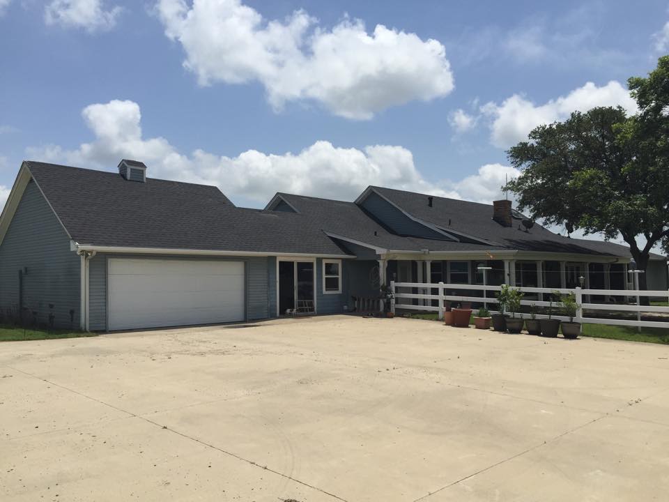 A large house with a garage and a white fence