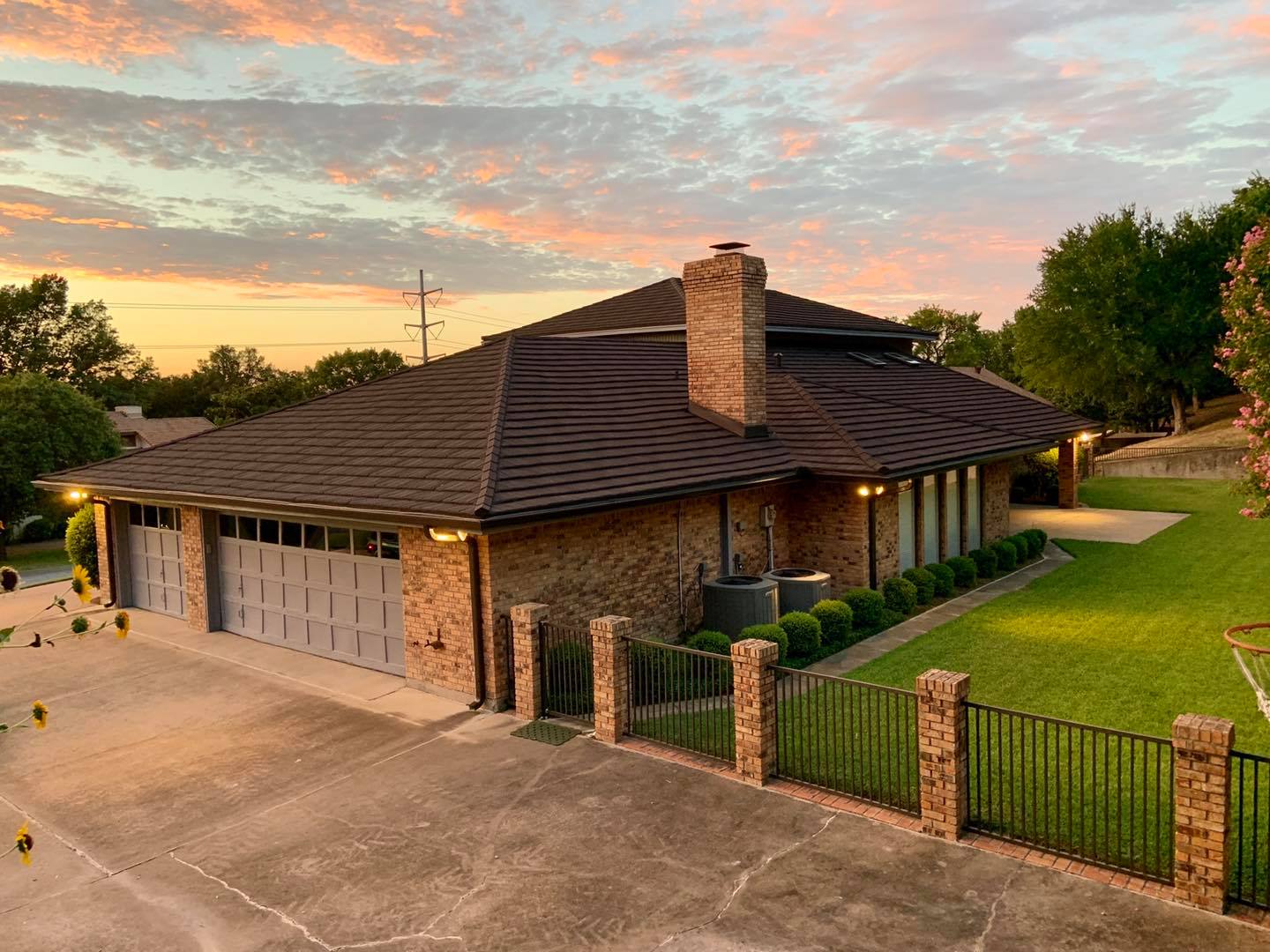A large brick house with a large garage and a fence in front of it.