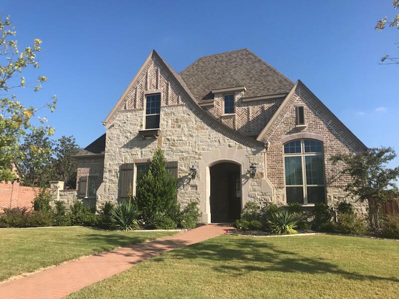 A large stone house with a brick walkway leading to it