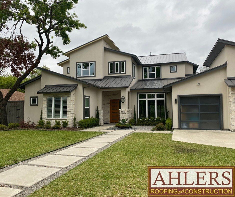 A large house with a sign that says ahlers roofing construction