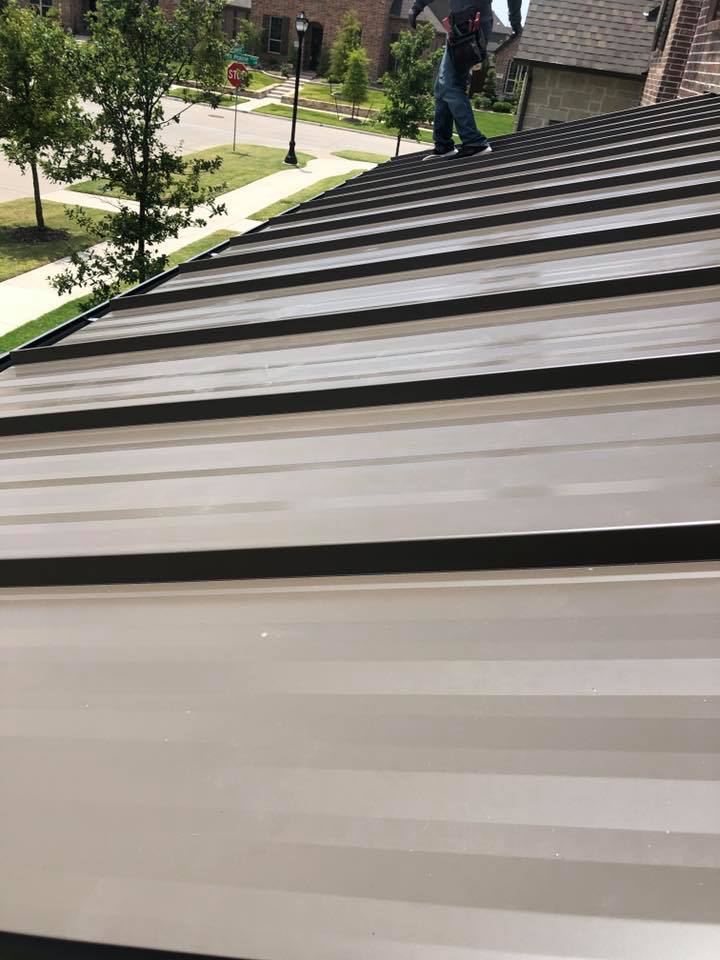 A man is standing on top of a metal roof.