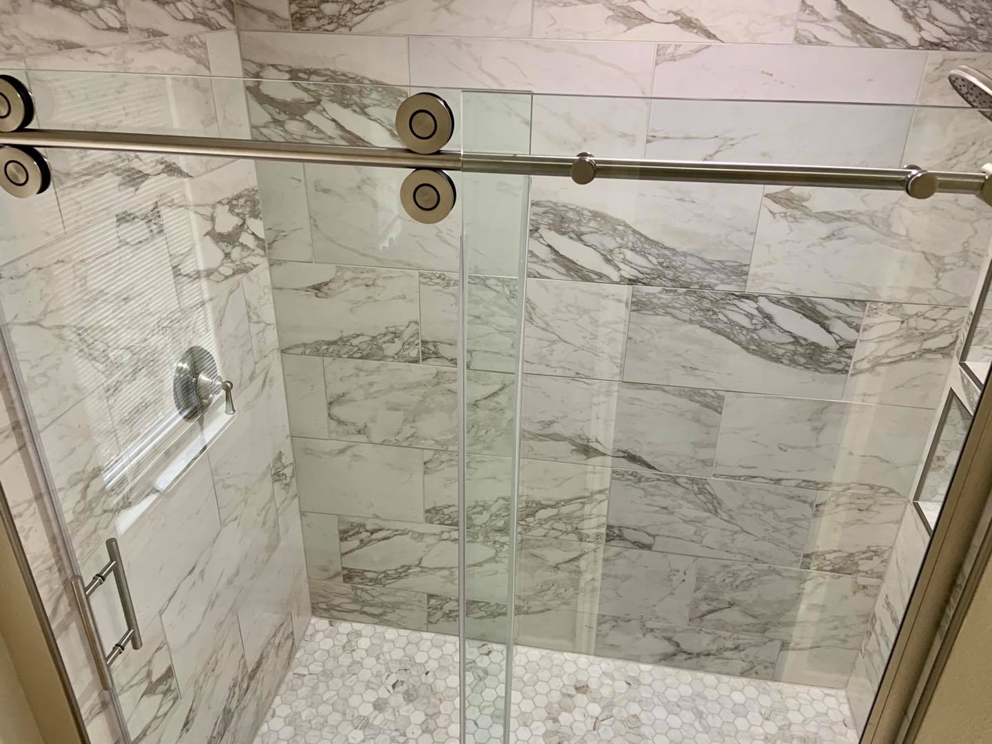 A bathroom with marble tiles and a sliding glass shower door.