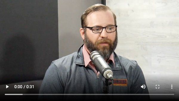 A man with a beard and glasses is talking into a microphone