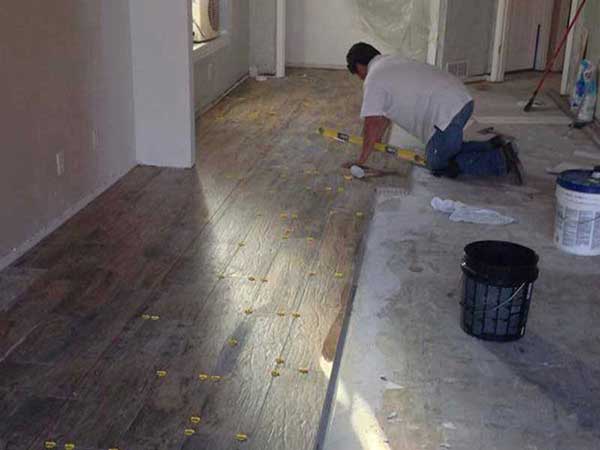 A man is working on a wooden floor in a room.
