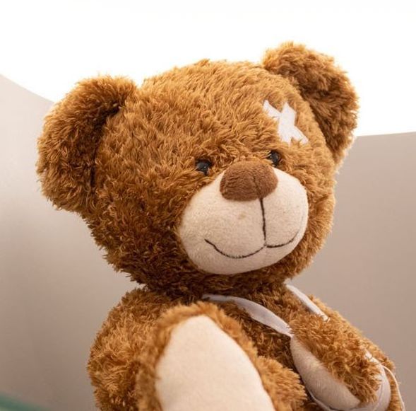 Ein Teddybär mit einem Verband auf dem Kopf sitzt auf einem Sofa.