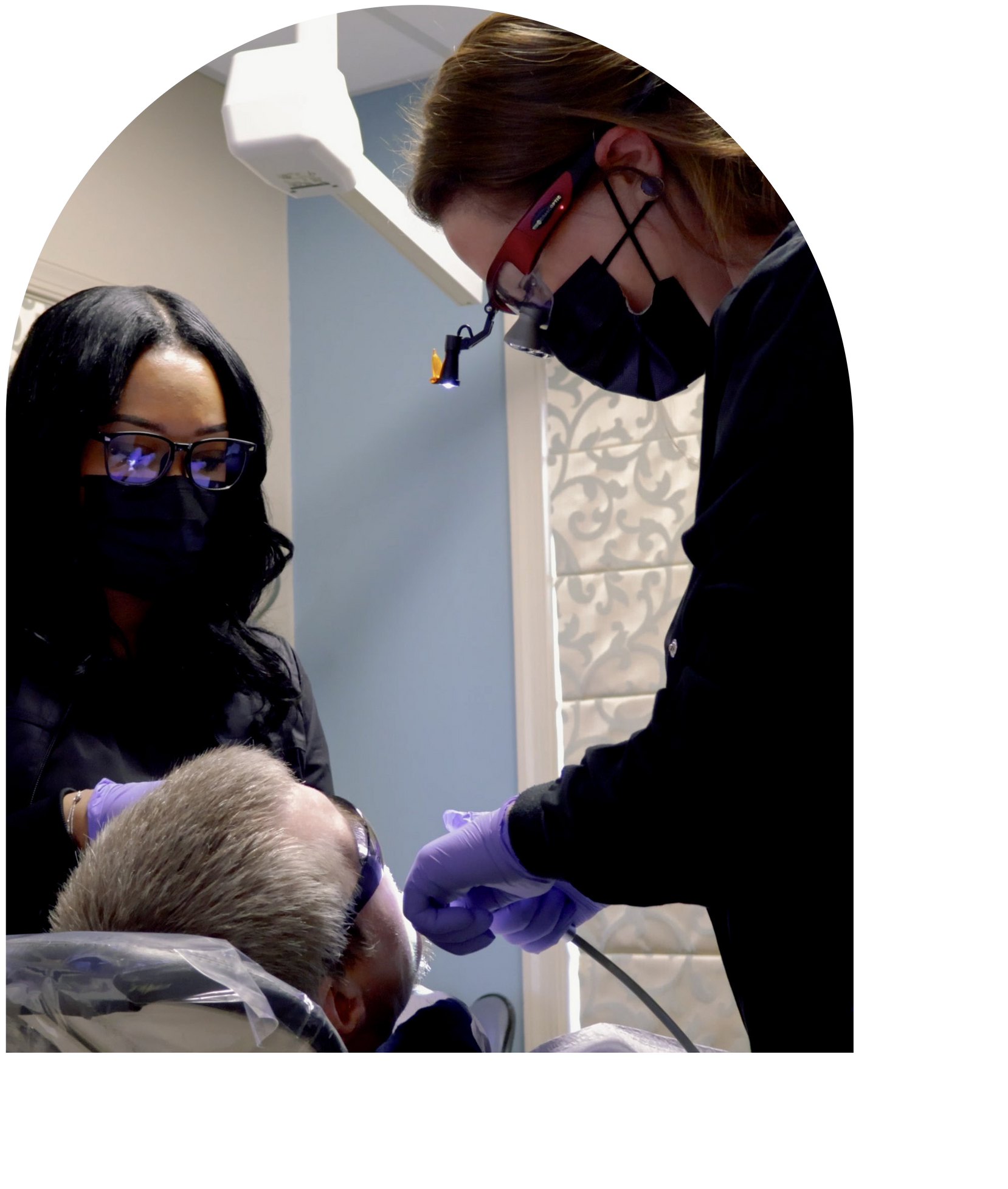 Dentist showing patient a mirror at Vail Dental Associates in Hunt Valley. Patient smiles while looking.
