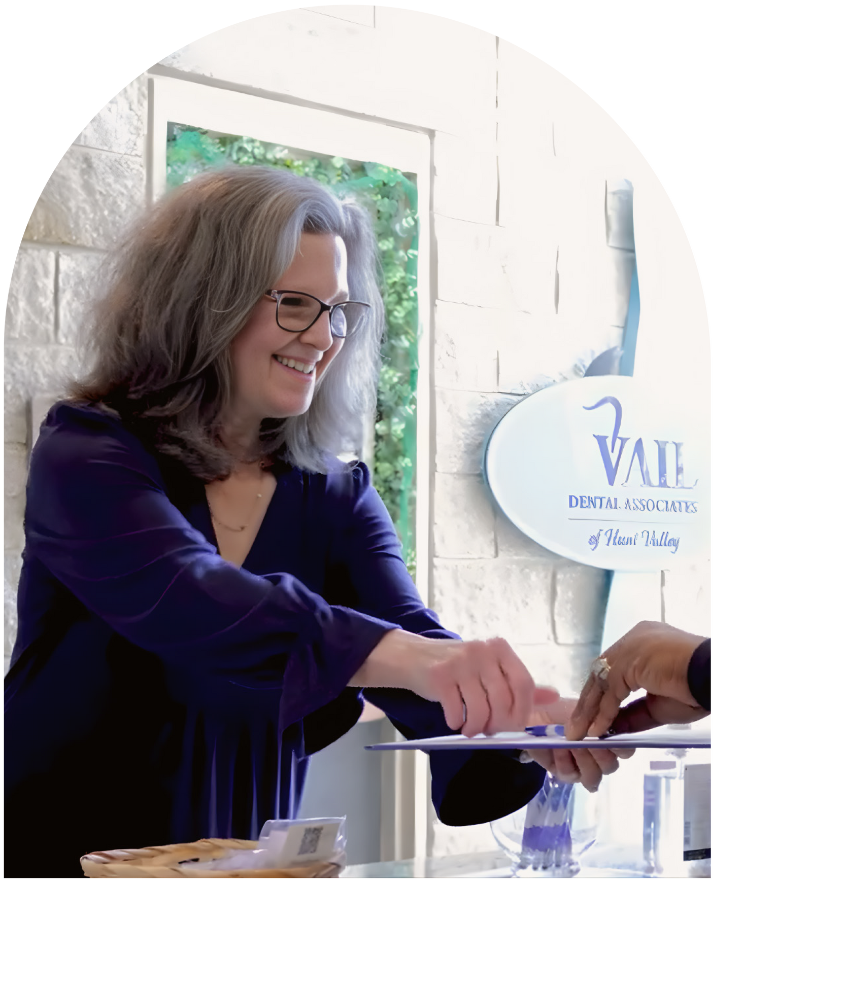 Nurse in blue scrubs points at paperwork with older patient in doctor's office.