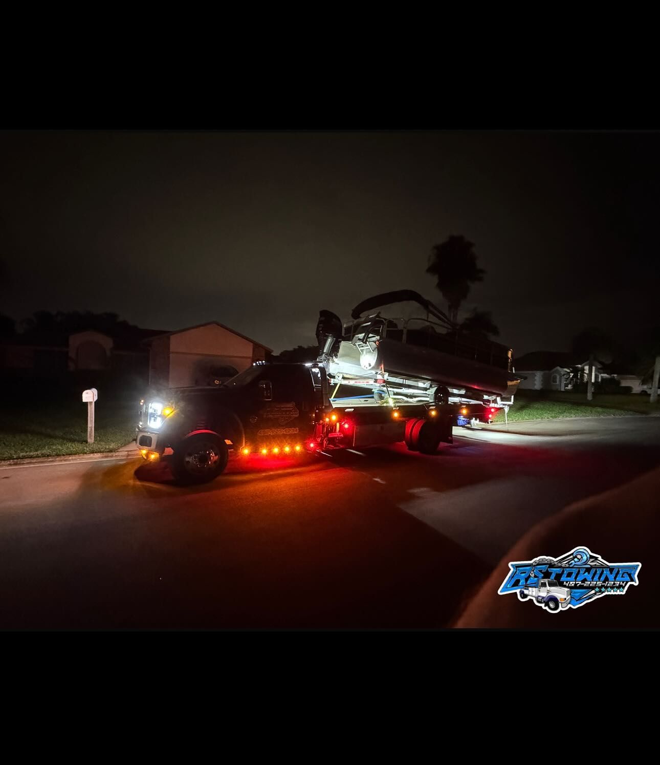 A tow truck is parked on the side of the road at night.