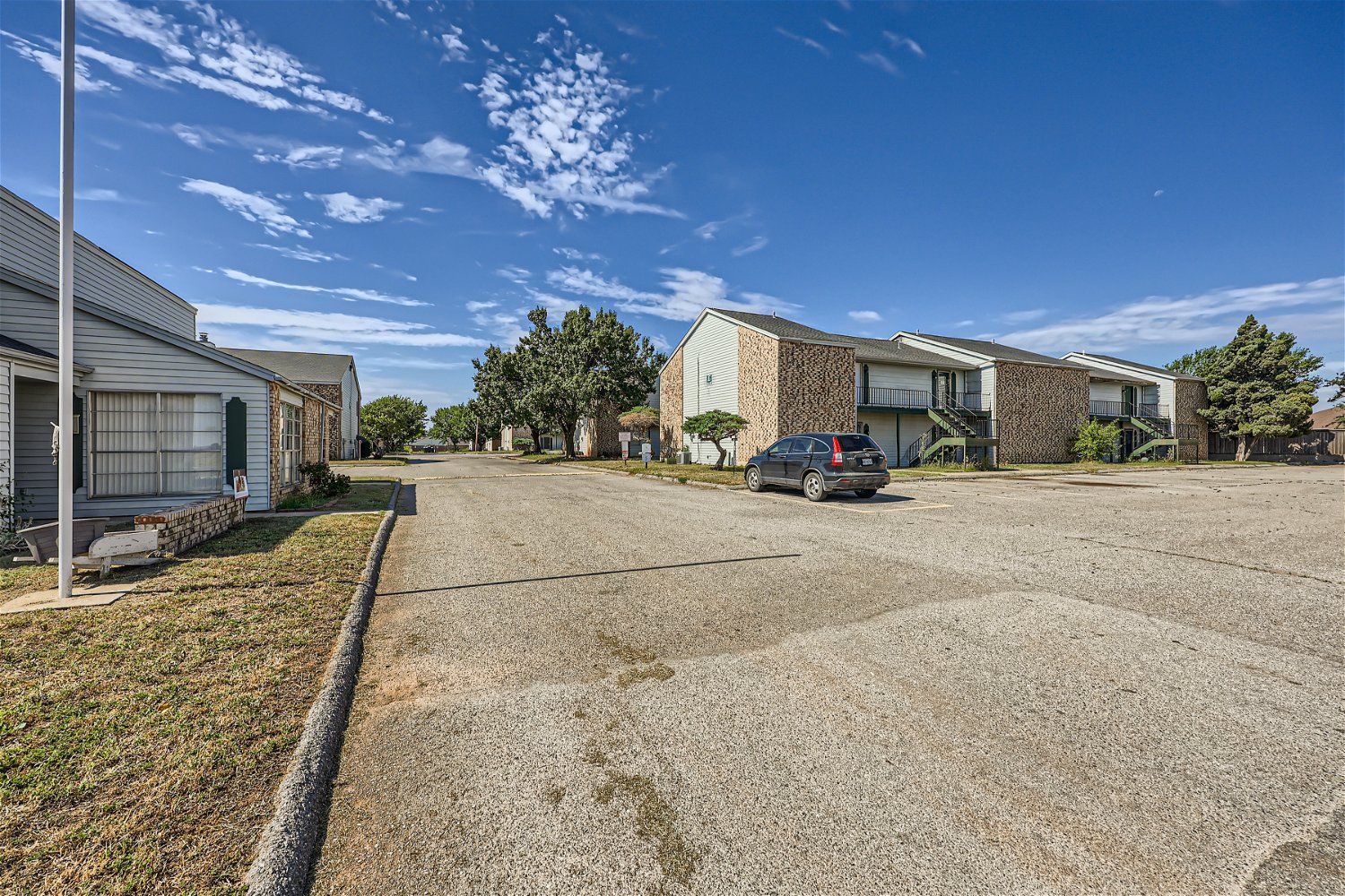 Apartment complex with parking lot on a sunny day.