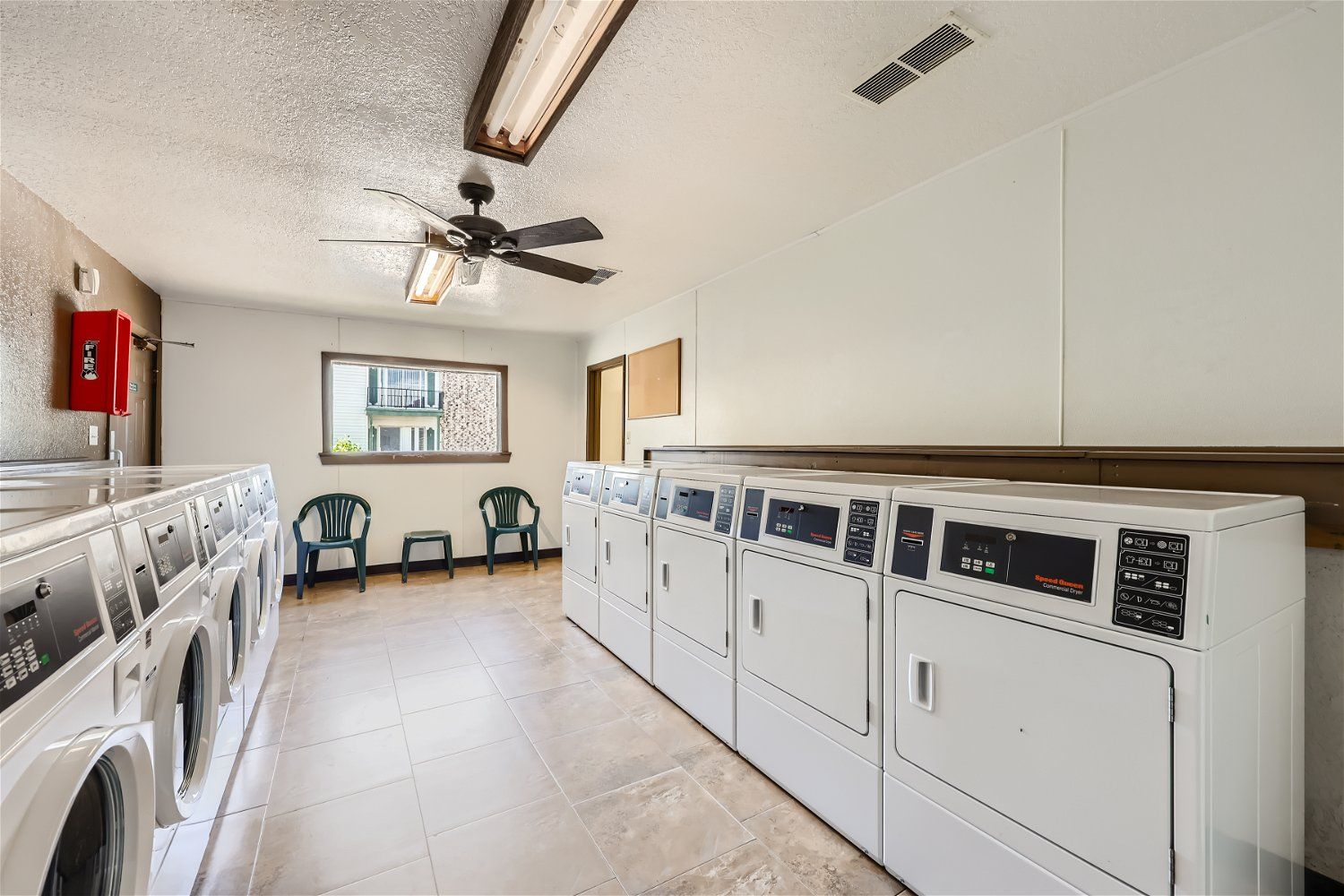 Check out our apartments for rent in Elk City, OK, at Crestview Commons.  These are the resident laundry facilities, with rows of washers and dryers, a ceiling fan, and a small window.