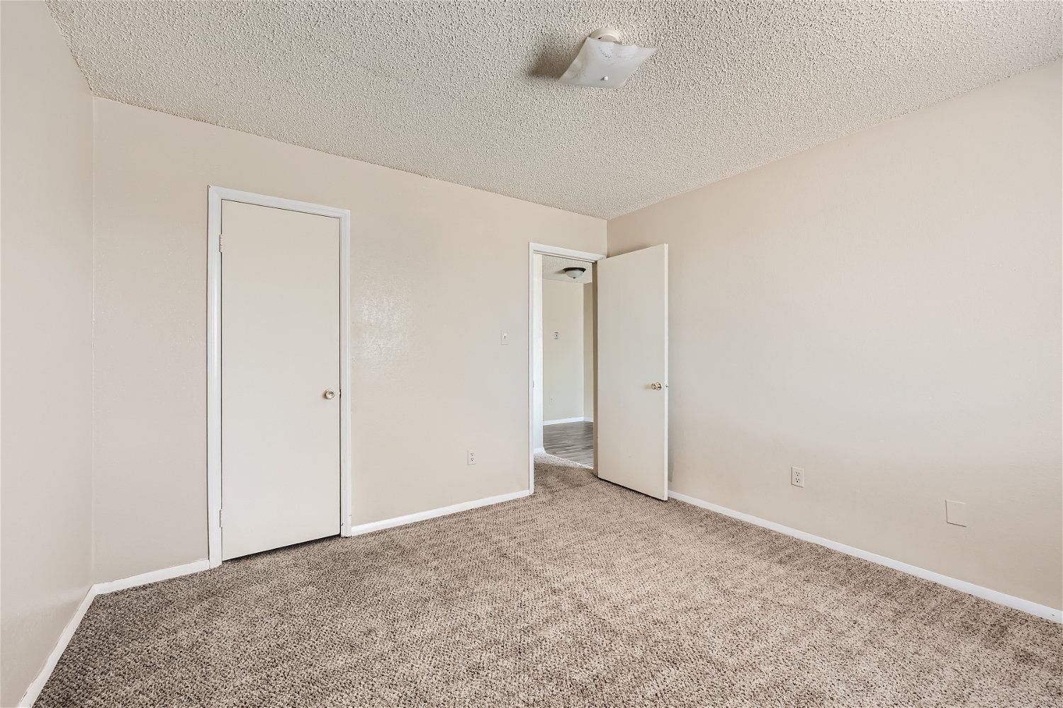 Check out our apartments for rent in Elk City, OK, at Crestview Commons. This room has tan carpet, beige walls, and white doors.