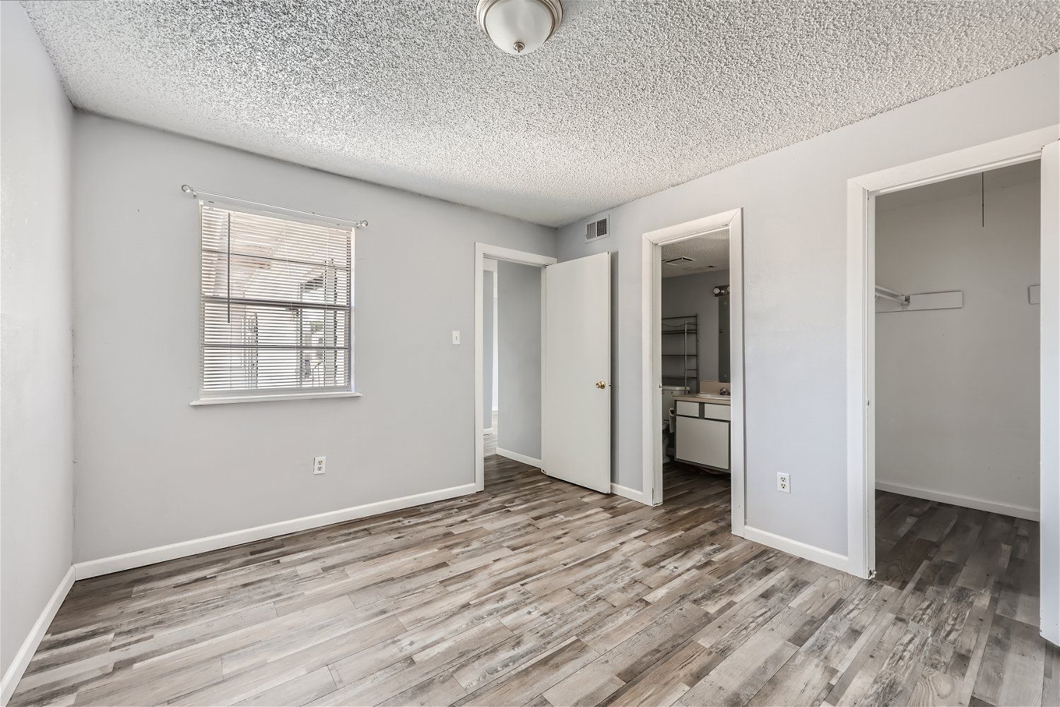 Check out our apartments for rent in Elk City, OK, at Crestview Commons. This room has gray walls, wood floors, three doorways, and a window with blinds.