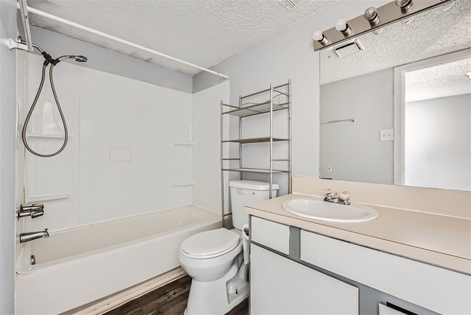 Check out our apartments for rent in Elk City, OK, at Crestview Commons. This apartment bathroom has a white tub, toilet, and vanity, shelving above the toilet, and a large mirror.