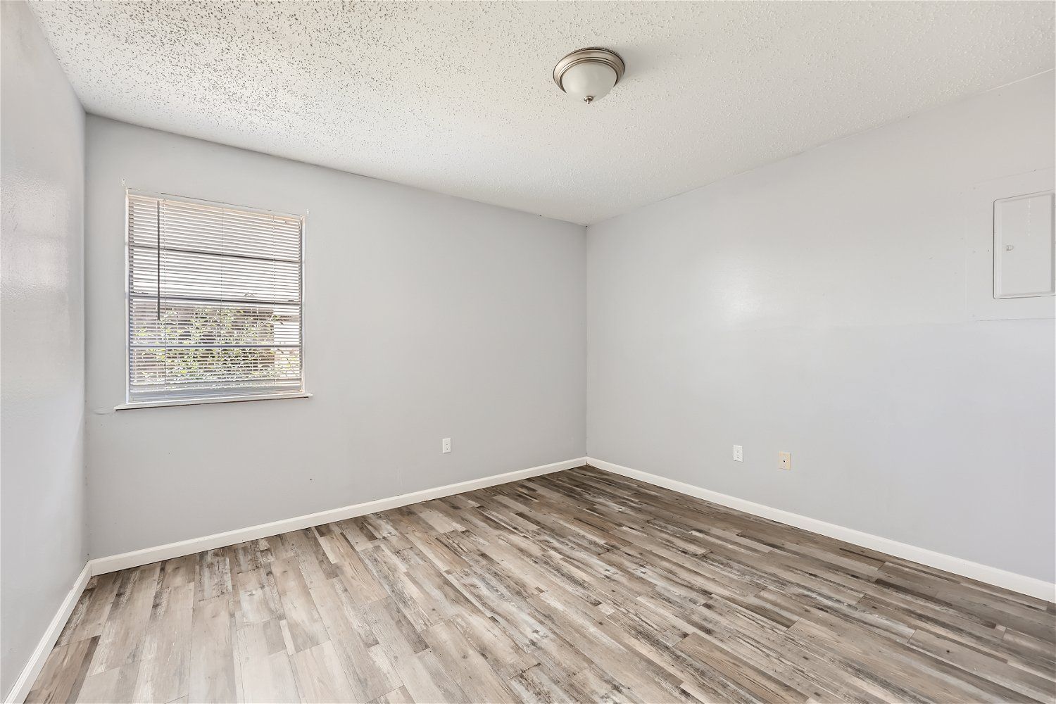 Check out our apartments for rent in Elk City, OK, at Crestview Commons. This room has gray walls, wood-look flooring, and a window with blinds.