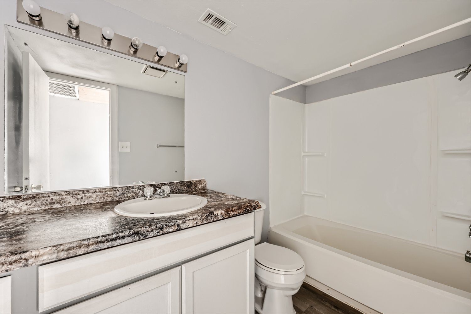 Check out our apartments for rent in Elk City, OK, at Crestview Commons. This apartment bathroom has a white vanity, tub/shower, and toilet; gray walls anda  granite countertop.