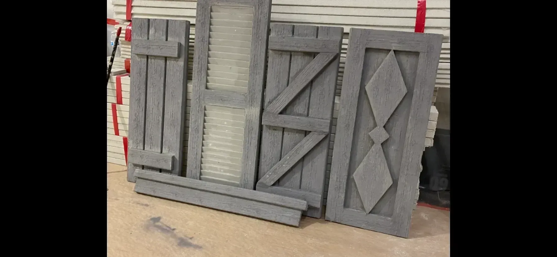 Gray wooden panels and crate-like doors leaning together in a workshop setting
