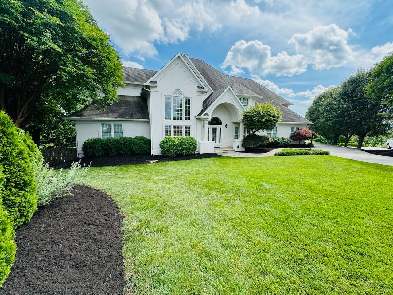 A large white house with a lush green lawn in front of it.