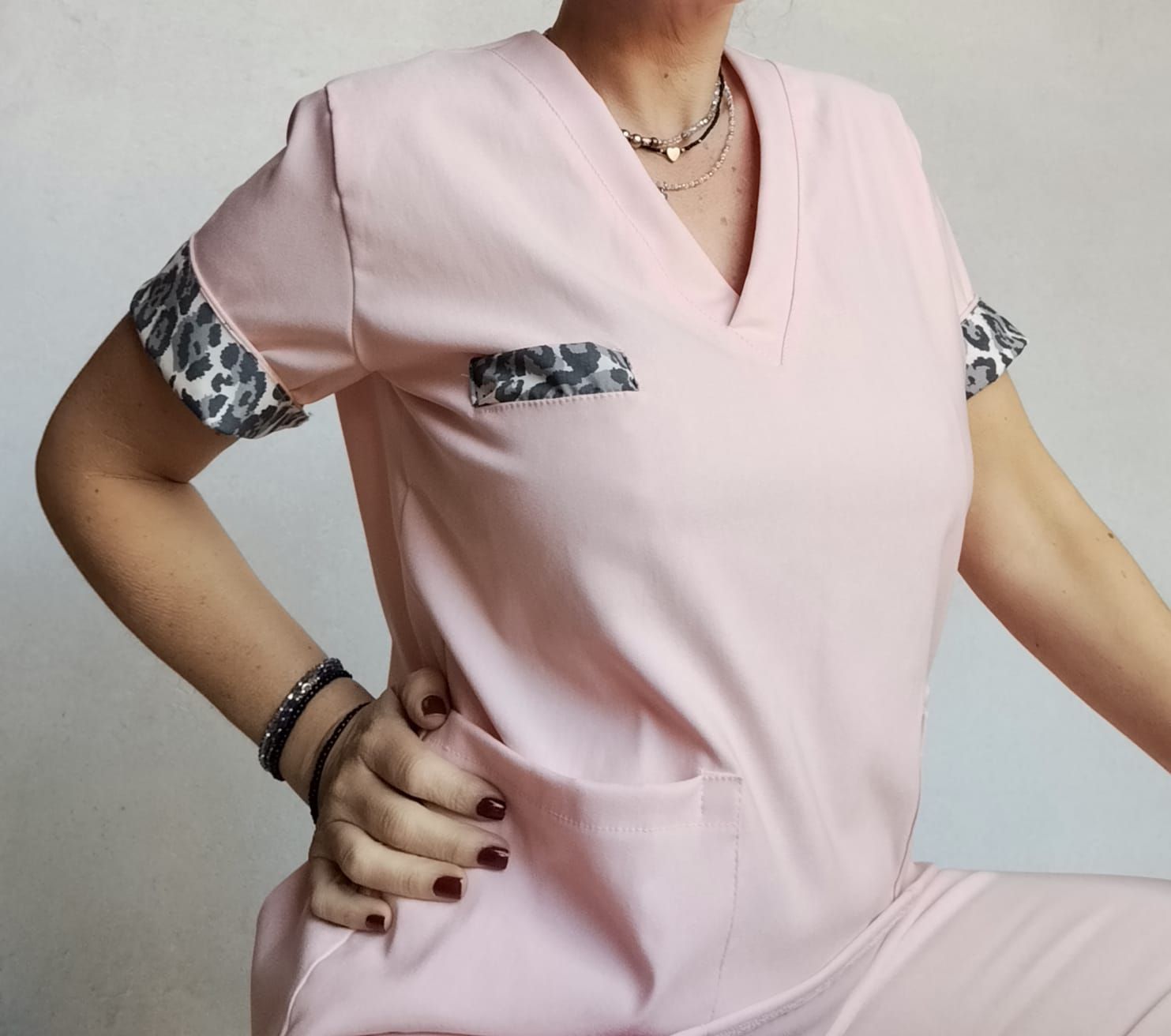 Persona que viste un uniforme médico de color rosa claro con detalles en estampado de leopardo.